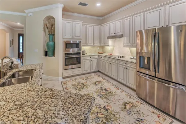 a kitchen with granite countertop a refrigerator and a stove top oven