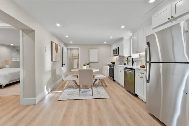 a kitchen with stainless steel appliances a refrigerator a stove a sink dishwasher with a dining table and chairs