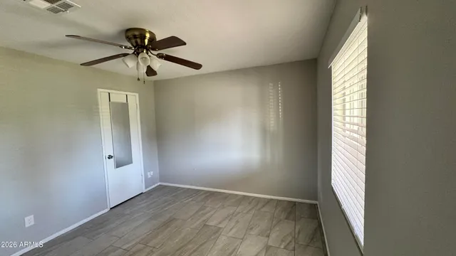 an empty room with windows and fan
