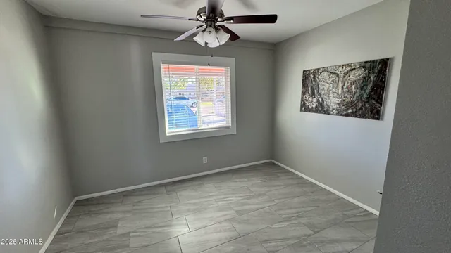 an empty room with windows and fan