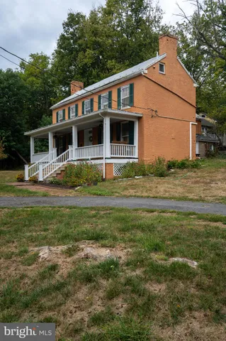a view of a white house with a large tree in front