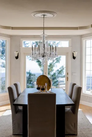 a dining room with furniture large windows and a chandelier