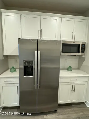 a kitchen with a refrigerator and white cabinets