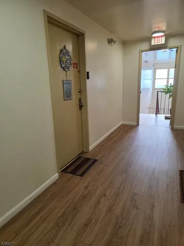 an empty room with wooden floor mirror and windows