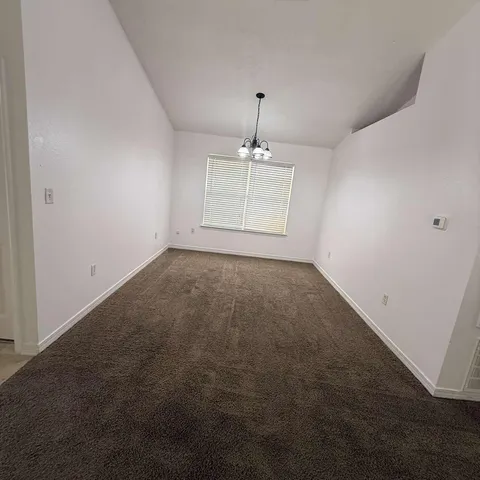 an empty room with a chandelier fan and windows