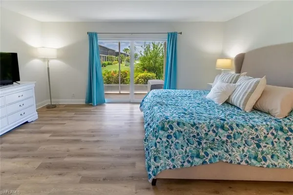 a bedroom with a large bed and a flat tv screen on dresser