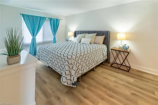 a bed sitting in a bedroom next to a window and a potted plant