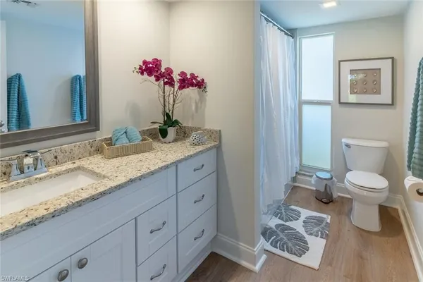a bathroom with a granite countertop sink a toilet and a mirror