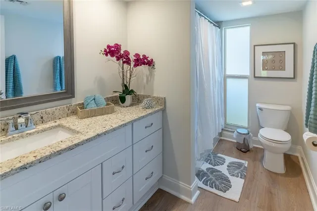 a bathroom with a granite countertop sink a toilet and a mirror