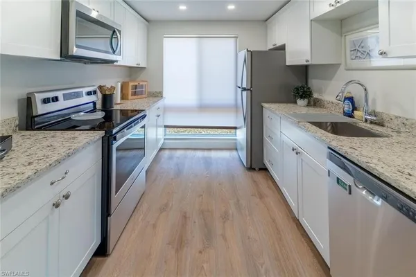 a kitchen with kitchen island granite countertop a sink stove and refrigerator