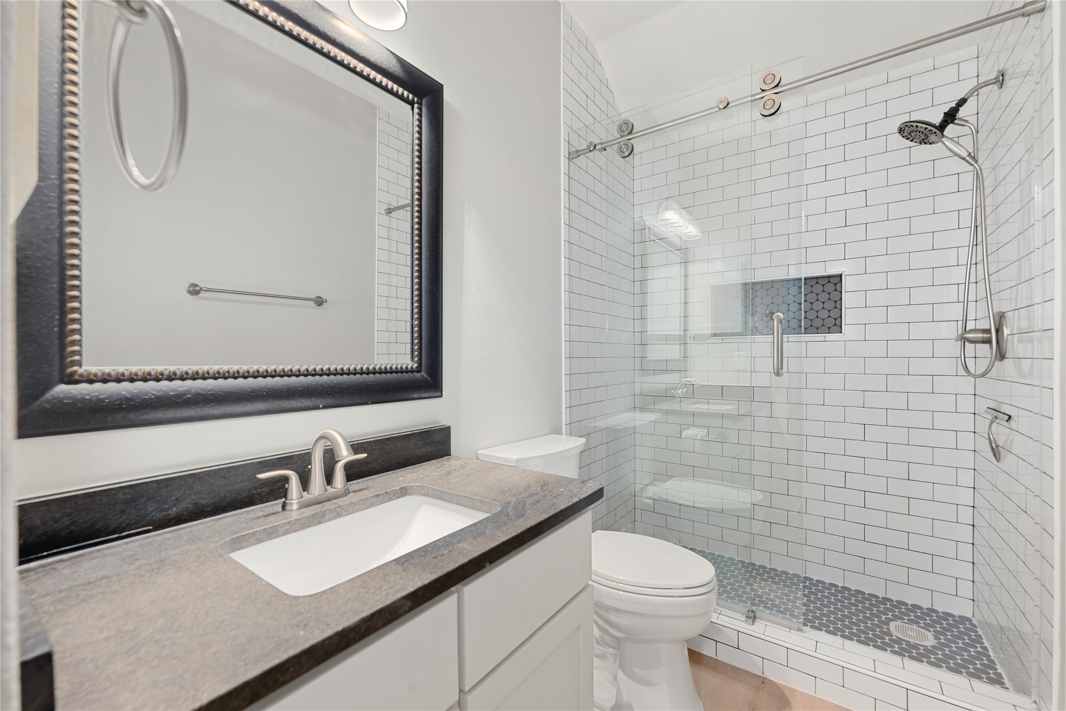 98 Herons Flight Place Spring, TX 77389 - Photo 18 of 29 Updated secondary bath with subway tile walk-in shower, penny tile flooring, and granite-topped vanity.
