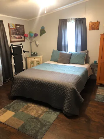 a bedroom with a bed painting on wall and a window