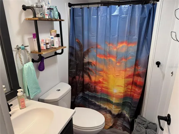 a bathroom with a sink a toilet and shower curtain