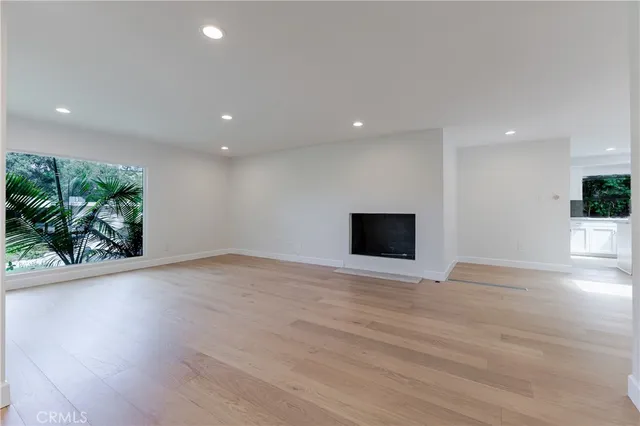 a view of empty room with wooden floor and potted plants