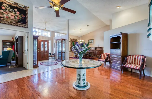 a dining room with wooden floor a chandelier a glass table and chairs