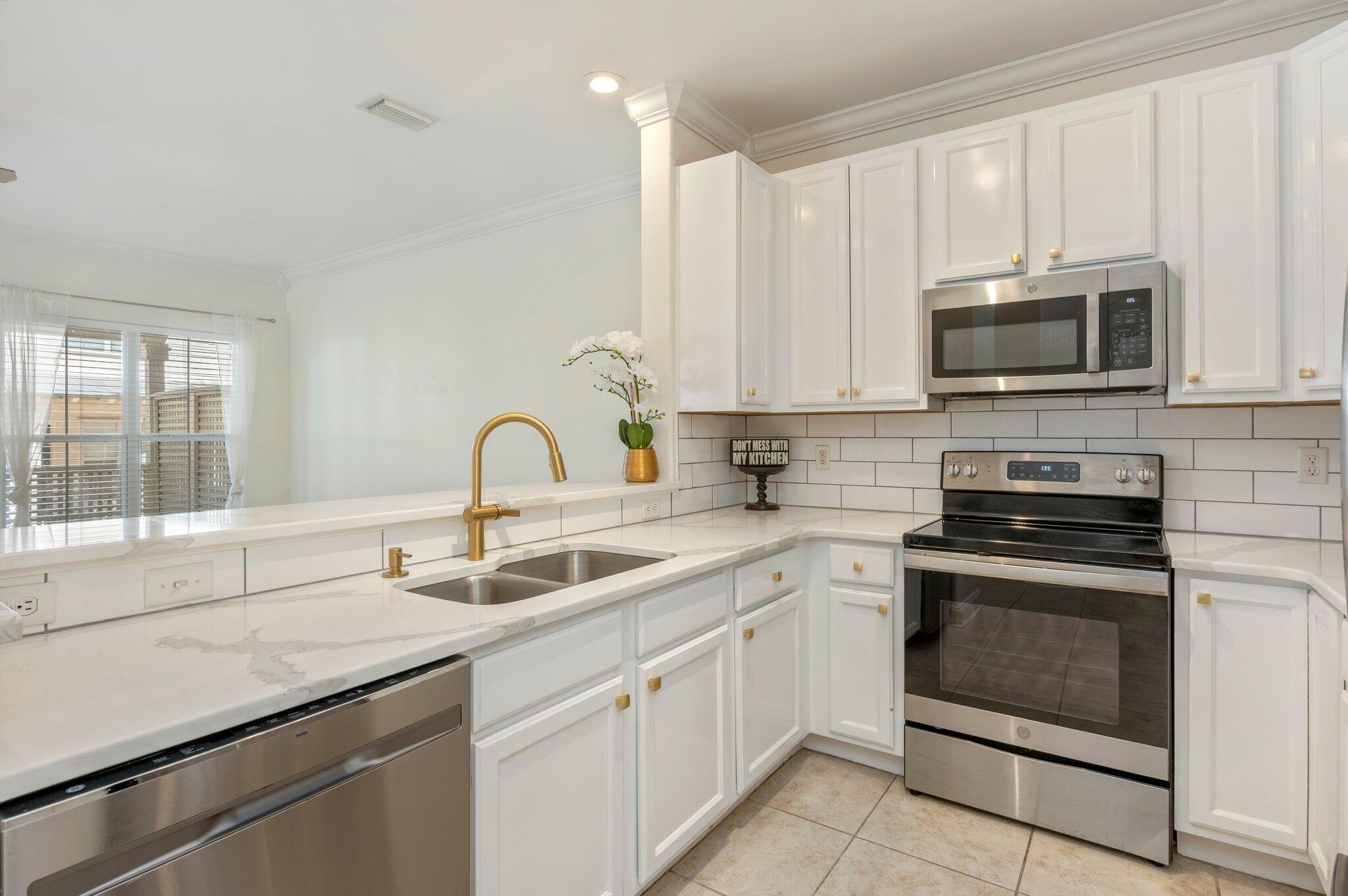a kitchen with white cabinets a sink and a stove with wooden floor