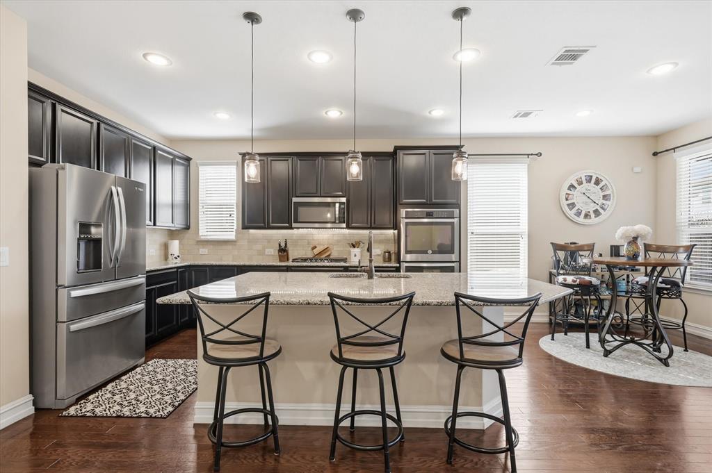 824 Pinnacle Ridge Road Fort Worth, TX 76052 - Photo 13 of 40 a kitchen with stainless steel appliances kitchen island granite countertop a dining table chairs refrigerator and microwave