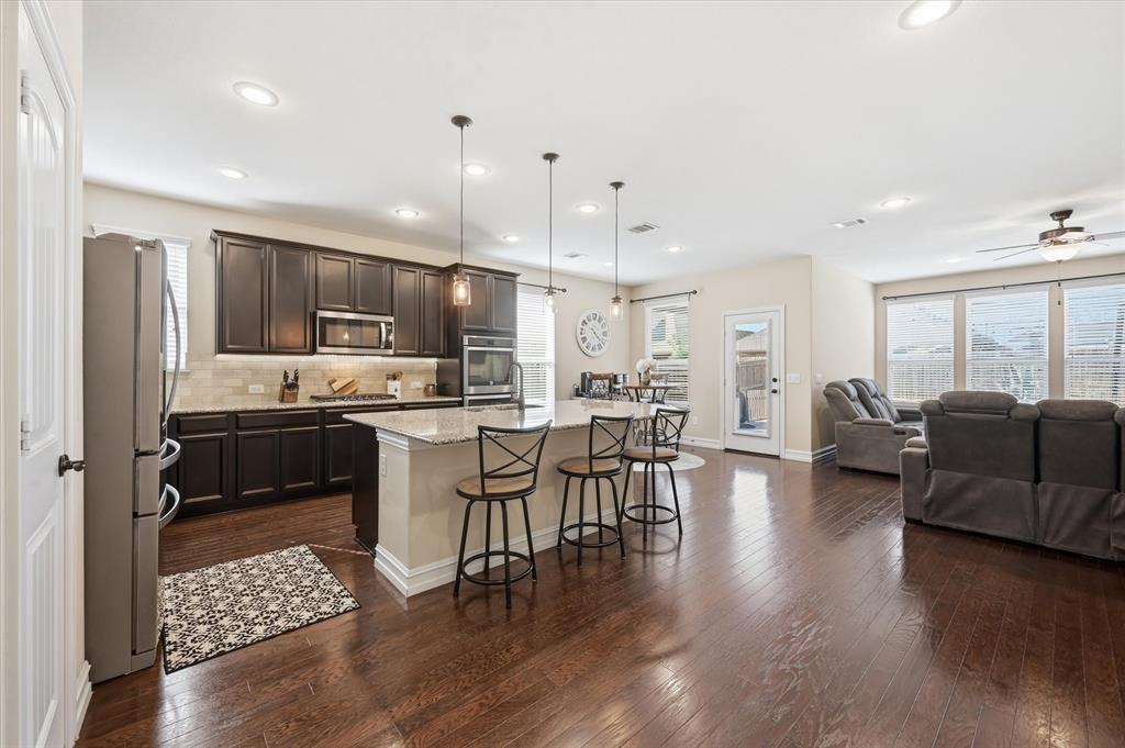 824 Pinnacle Ridge Road Fort Worth, TX 76052 - Photo 14 of 40 a kitchen with stainless steel appliances granite countertop a refrigerator a stove top oven a dining table and chairs with wooden floor