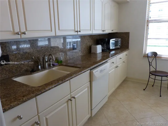 a kitchen with granite countertop a sink a stove and cabinets