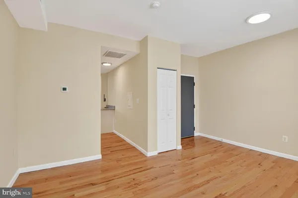 a view of an empty room with wooden floor and a bathroom
