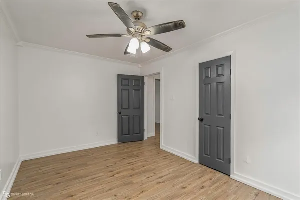 an empty room with wooden floor fan and windows