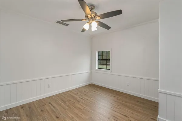an empty room with wooden floor closet and windows