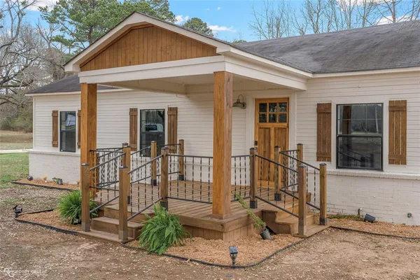 a view of a wooden house with a yard potted plants