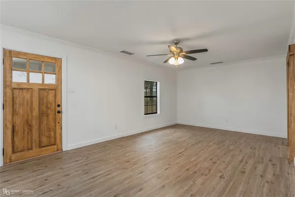 a view of an empty room with window and wooden floor