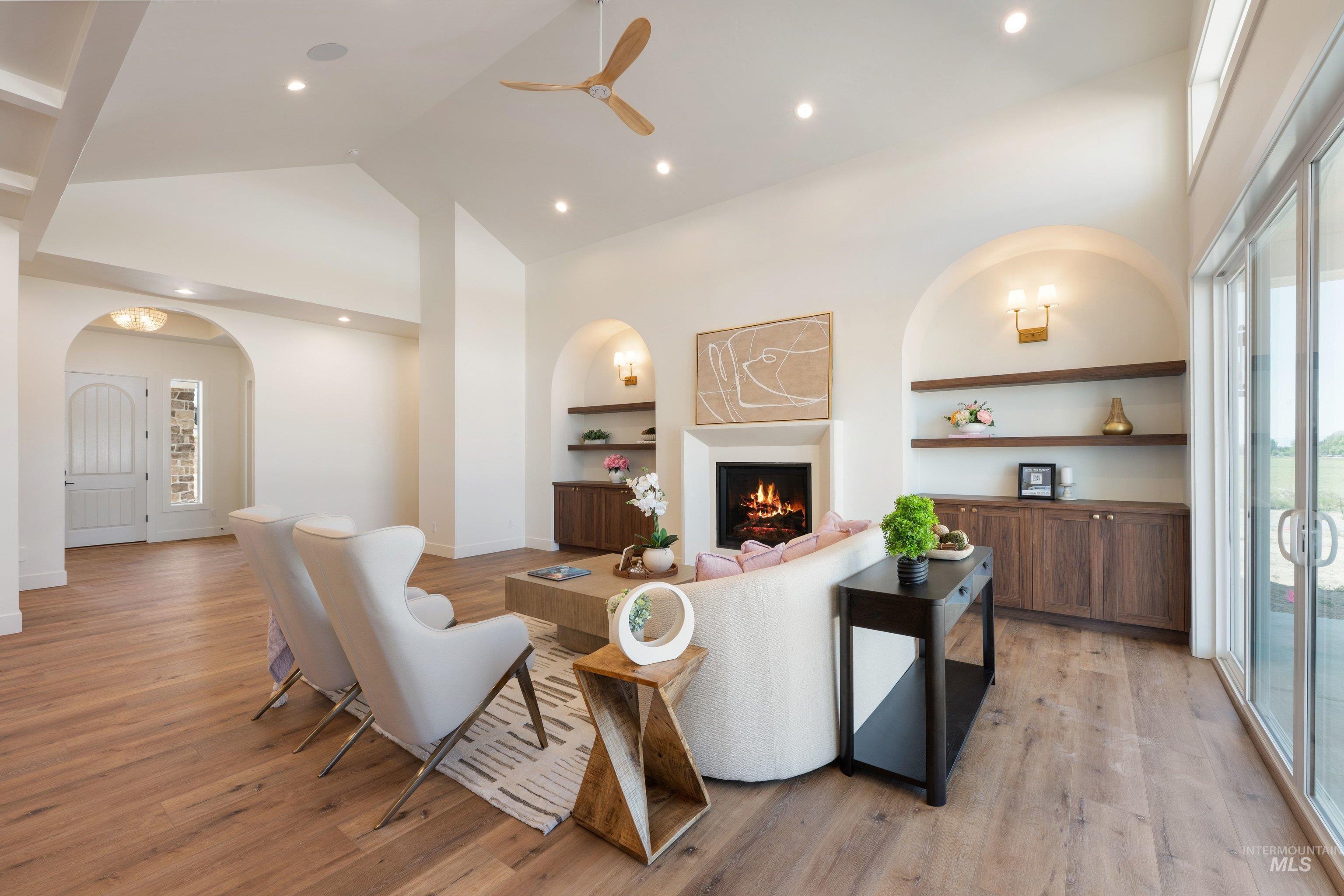 24821 Ardmore Court Caldwell, ID 83607 - Photo 12 of 43 Living area featuring vaulted ceilings, wood-finish flooring, a contemporary fireplace, and built-in shelving with cabinetry