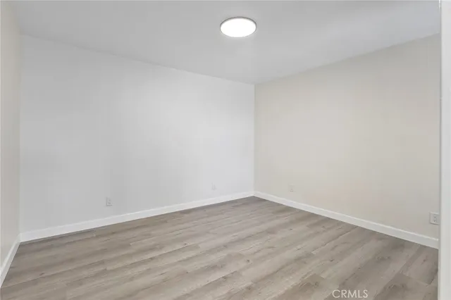 a view of an empty room with wooden floor and fan