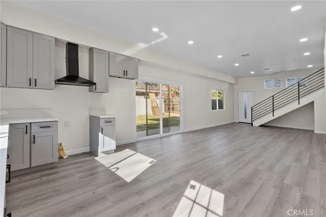 a living room with hard wood floors and a kitchen
