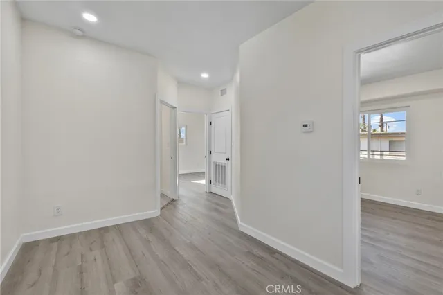 a view of a hallway with wooden floor and a bathroom