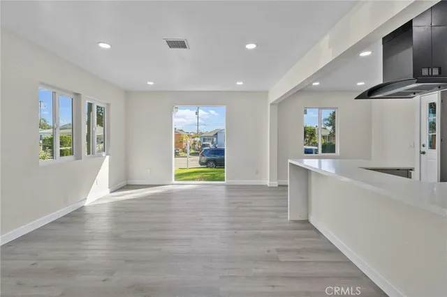 a view of an empty room with window and wooden floor
