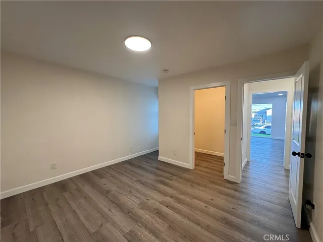 a view of an empty room with wooden floor and a bathroom