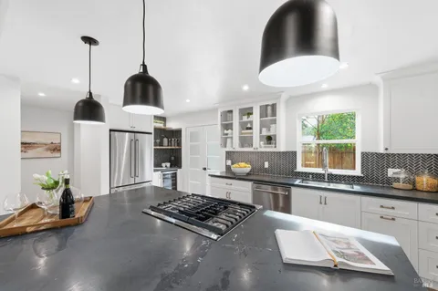 a kitchen with stainless steel appliances granite countertop a stove a sink a window and chairs