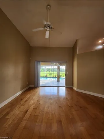 a view of empty room with wooden floor and fan