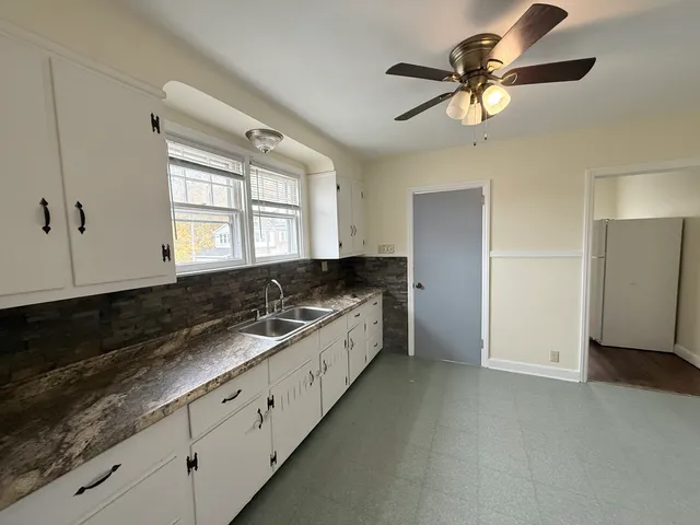 a large white kitchen with a large window appliances and cabinets