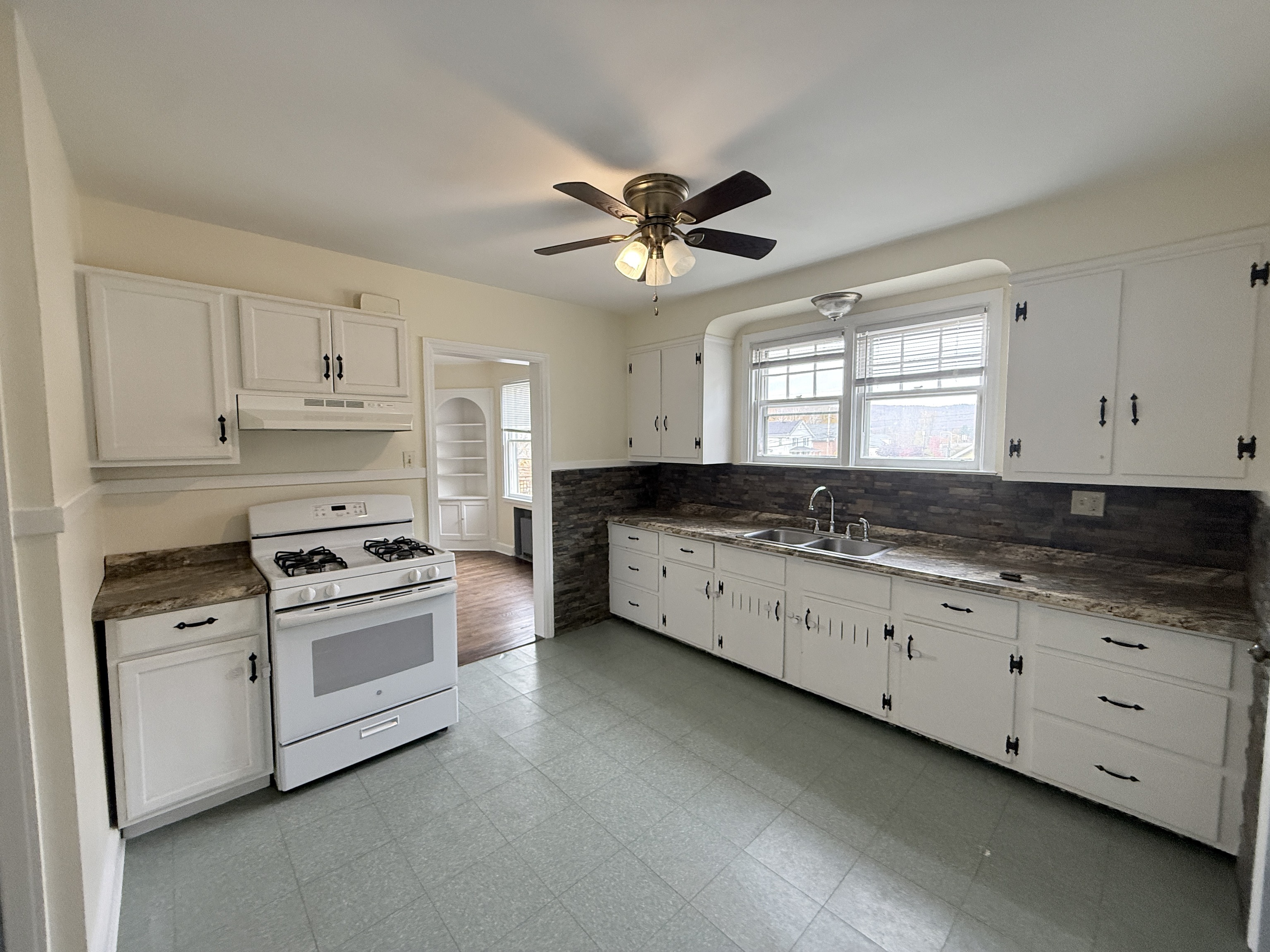 89 Hillside Avenue Torrington, CT 06790 - Photo 13 of 17 a kitchen with granite countertop a stove a sink and dishwasher with white cabinets