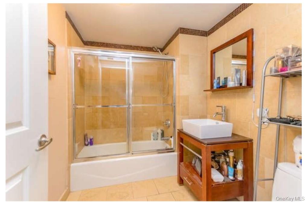 1490 Outlook Avenue, Unit 1A Bronx, NY 10465 - Photo 6 of 12 Bathroom with enclosed tub / shower combo, vanity, tile patterned flooring, and tile walls