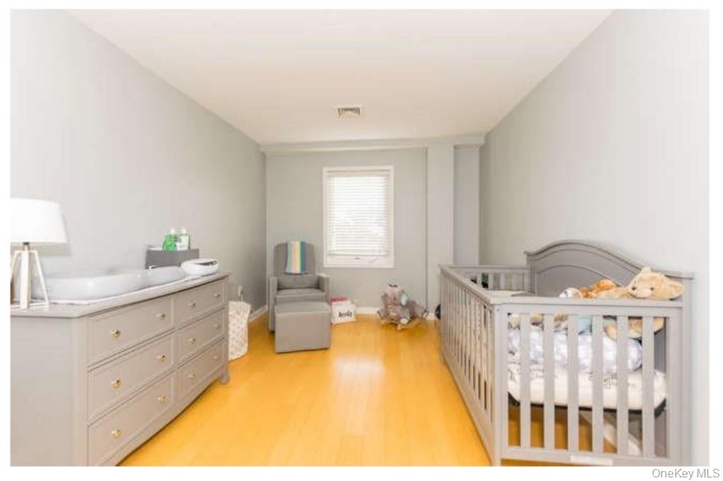 1490 Outlook Avenue, Unit 1A Bronx, NY 10465 - Photo 8 of 12 Bedroom featuring light wood-style flooring and a nursery area