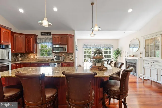 a kitchen with stainless steel appliances granite countertop a refrigerator a stove top oven a dining table and chairs