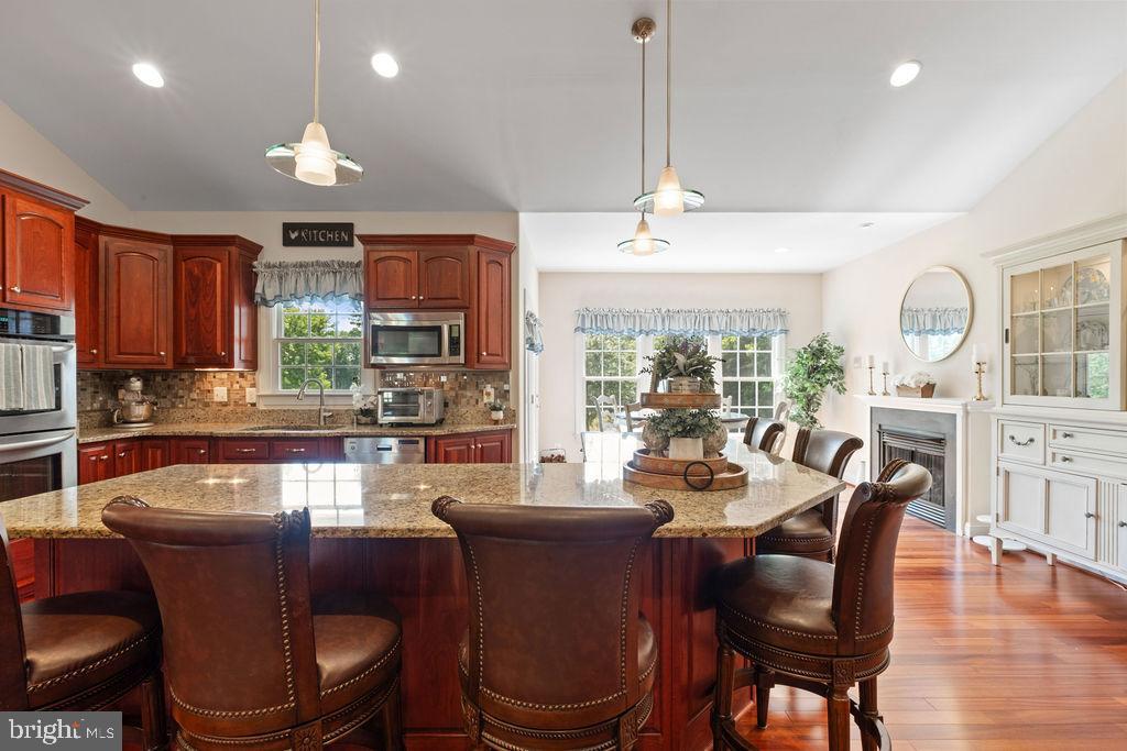 7609 Baileys Road Spotsylvania, VA 22551 - Photo 17 of 111 a dining room with wooden floor a chandelier a glass table and chairs