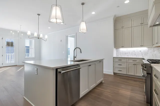 a kitchen with white cabinets stainless steel appliances and a chandelier