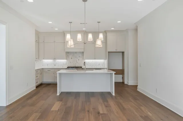 a kitchen with kitchen island white cabinets and wooden floor