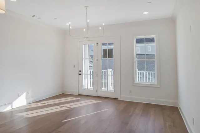 a view of an empty room with wooden floor and windows