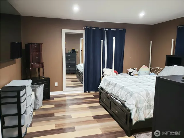 a large bedroom with a bed and a large mirror on the dresser