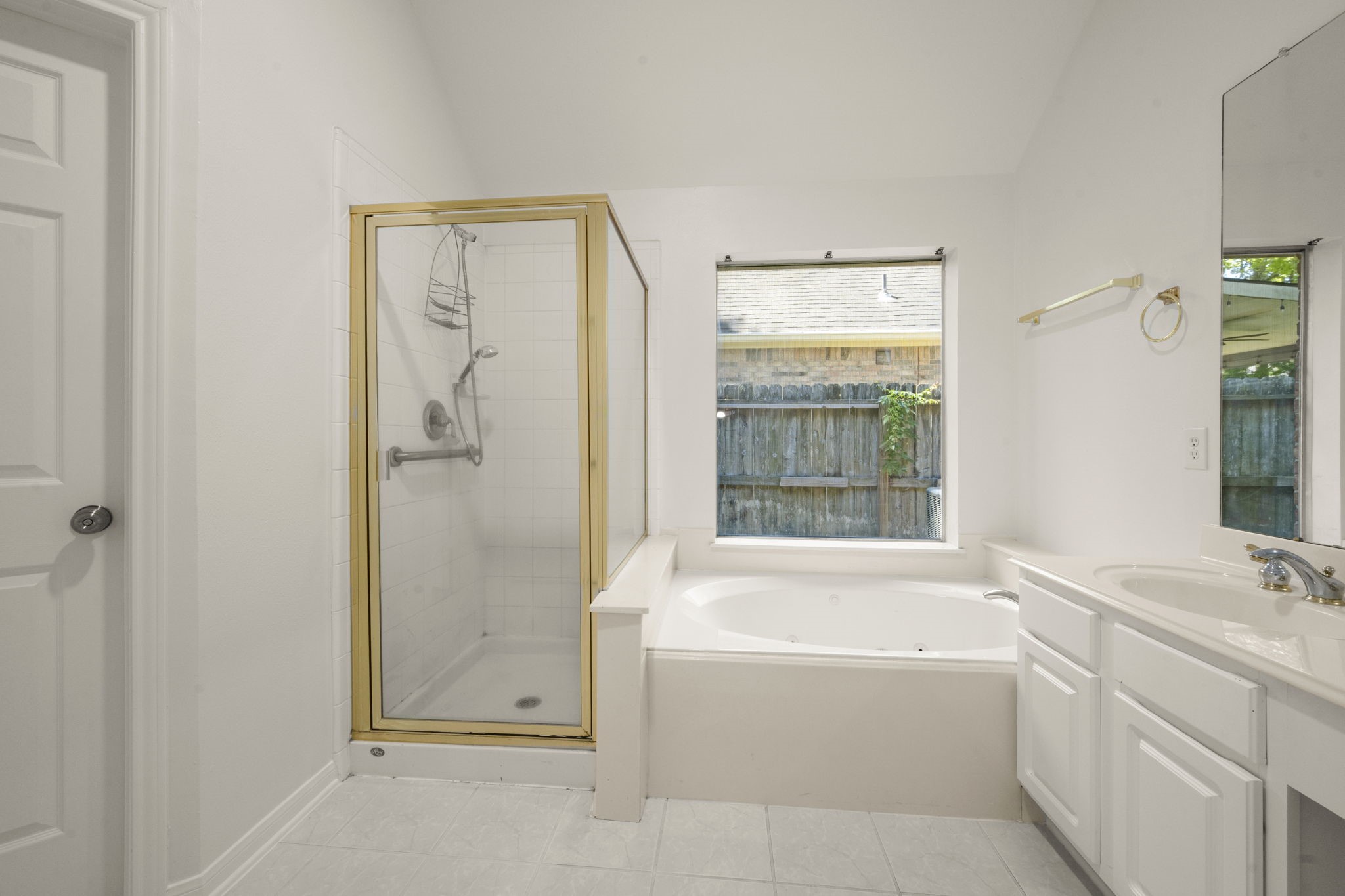 2018 Copperwood Park Lane Spring, TX 77386 - Photo 29 of 33 This primary bathroom features a spacious design with a glass-enclosed shower, a large soaking tub by a window, and a double-sink vanity, all in a bright and clean setting.