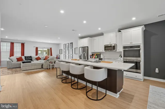 a living room with stainless steel appliances kitchen island granite countertop furniture a rug kitchen view and a refrigerator