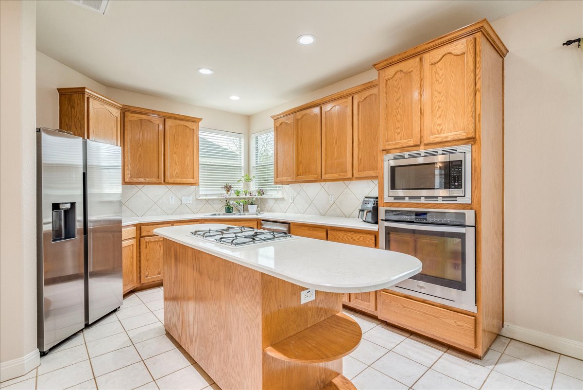 1077 Fairway Kyle, TX 78640 - Photo 15 of 40 a kitchen with stainless steel appliances granite countertop a stove a refrigerator a sink and cabinets