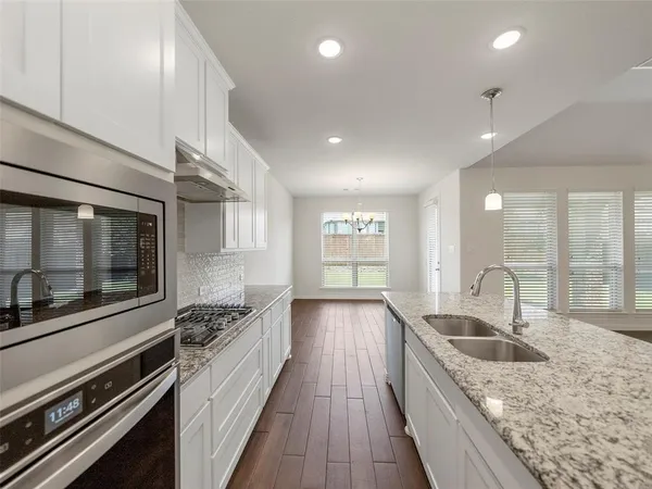 a kitchen with granite countertop a sink stove and cabinets